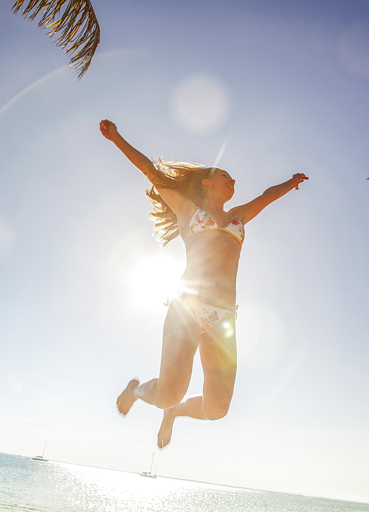 Caucasian woman in bikini jumping for joy