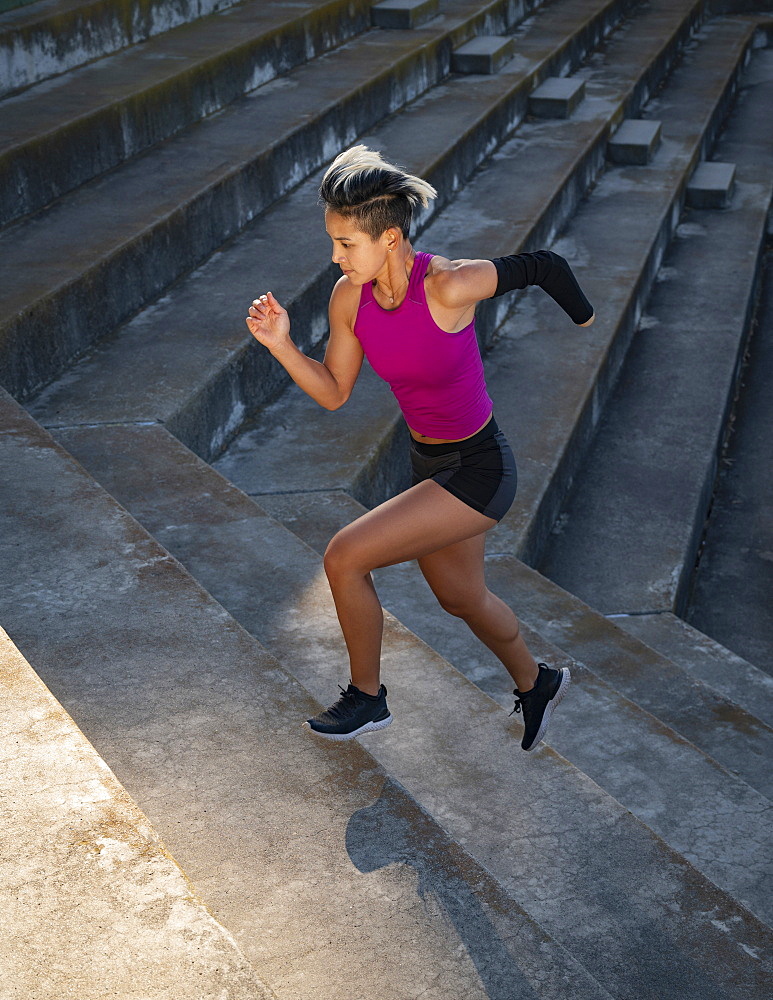 Athletic woman with amputated hand running up steps