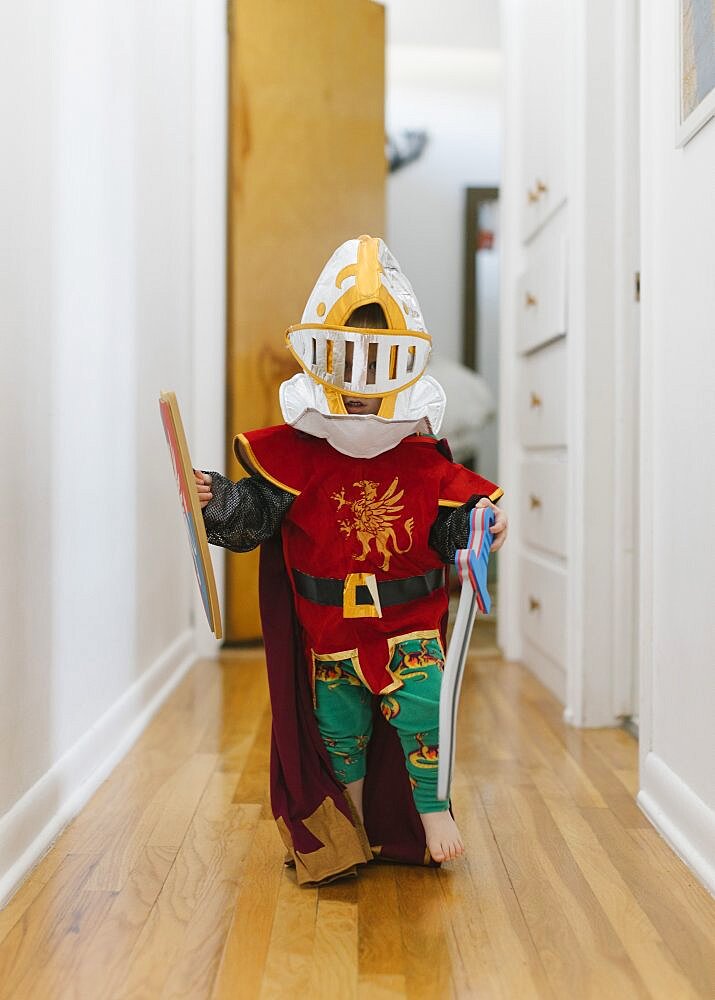 Toddler boy (2-3) in knight costume playing at home