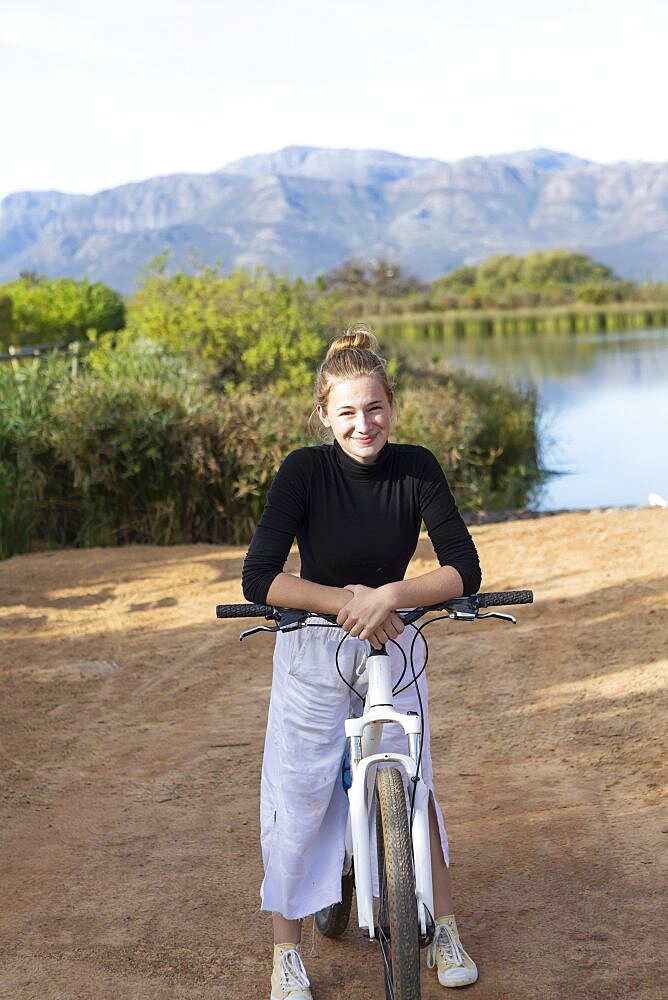 South Africa, Stellenbosch, Portrait of smiling teenage girl (16-17) on bike