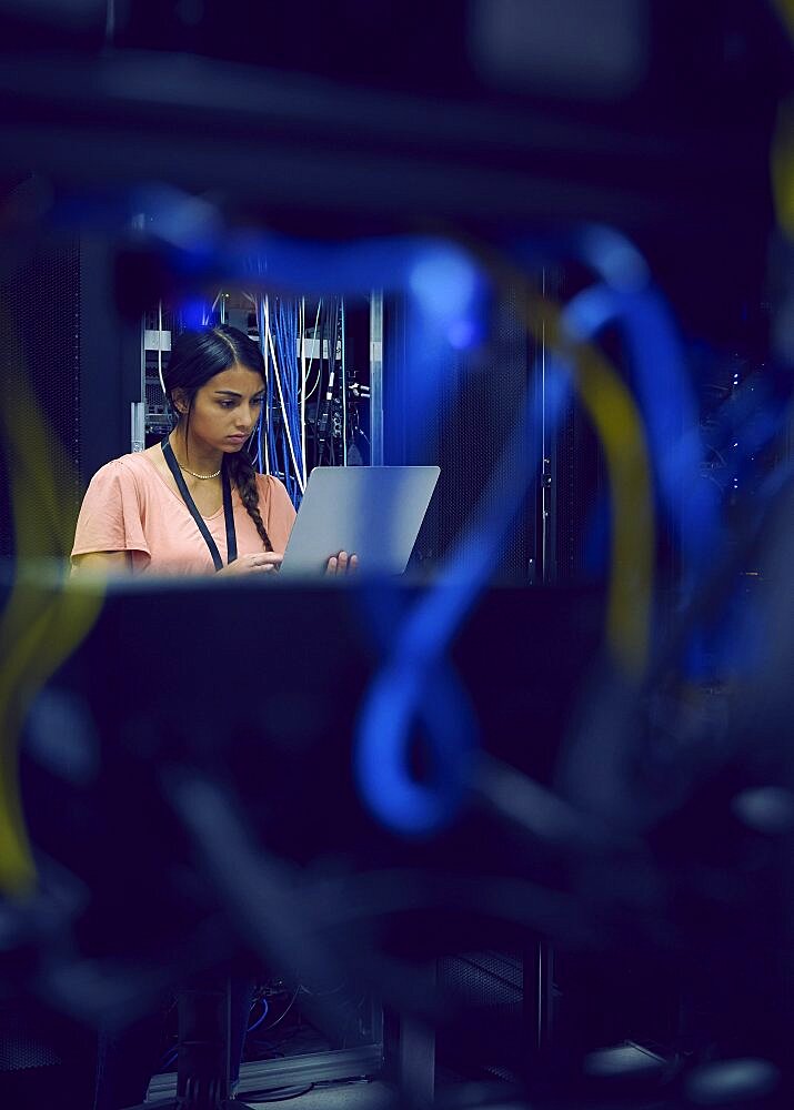 Female technician using laptop in server room