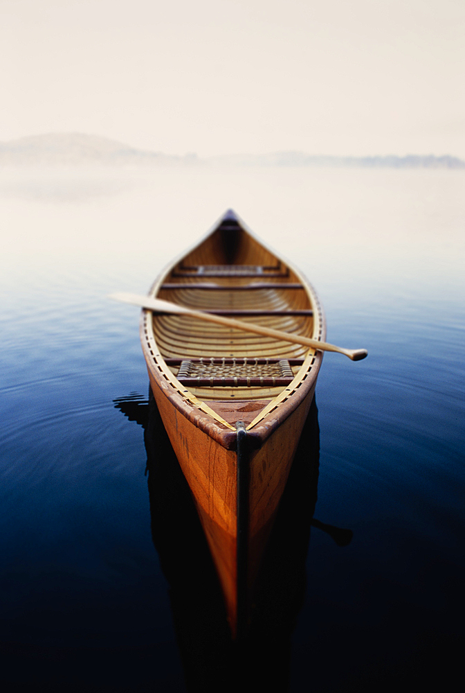 United States, New York, Canoe in morning mist on Lake Placid, Adirondacks State Park