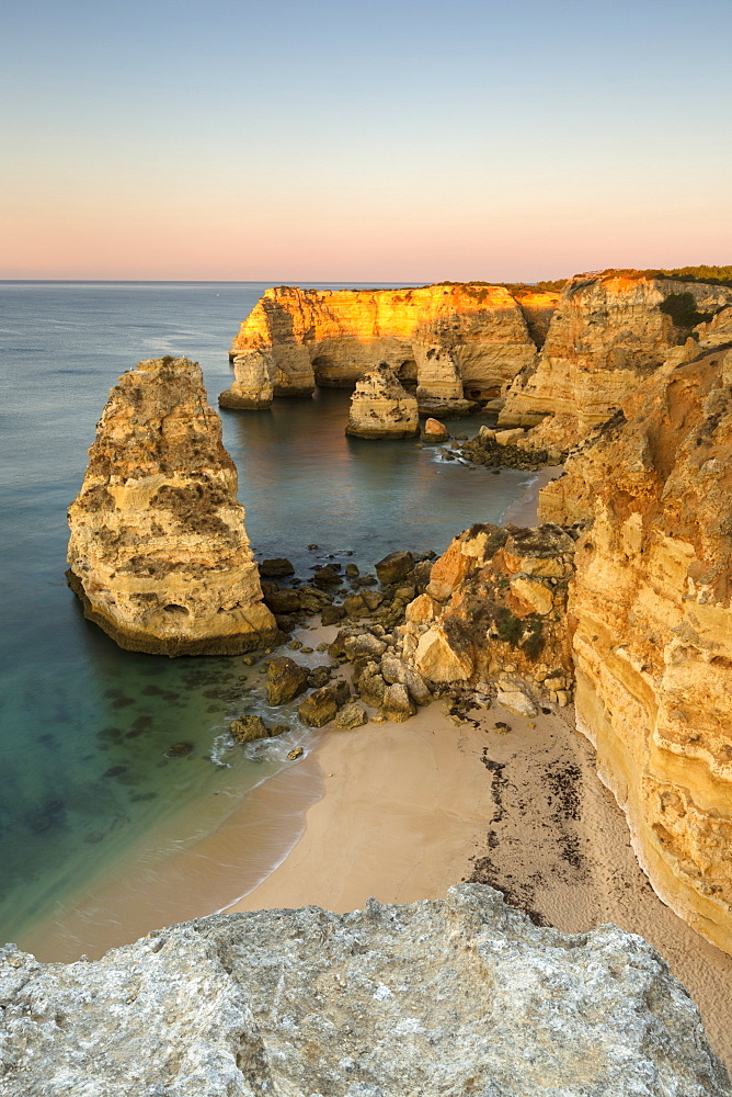 Sunrise on the cliffs and turquoise water of the ocean, Praia da Marinha, Caramujeira, Lagoa Municipality, Algarve, Portugal, Europe