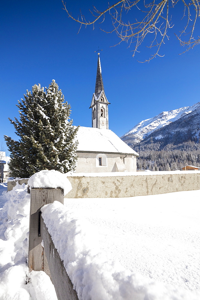 Alpine church covered with snow framed by blue sky, Cinuos, Canton of Graubunden, Engadine, Switzerland, Europe