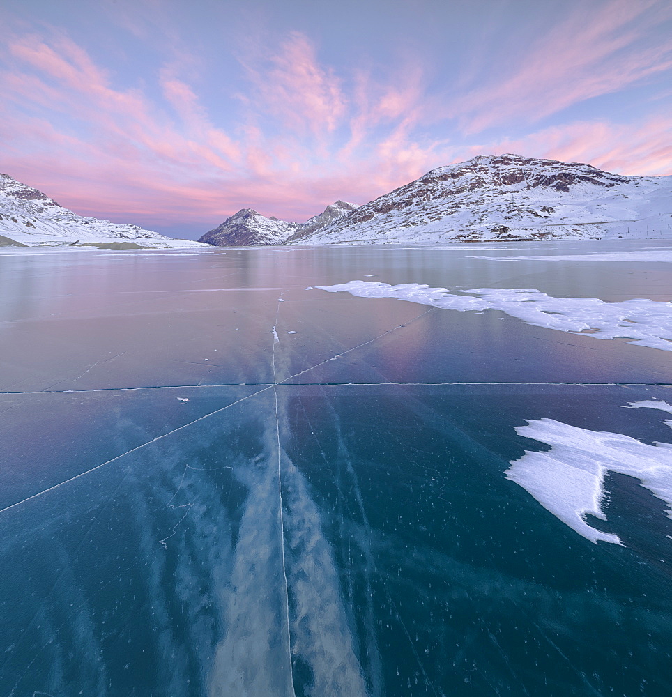 Panorama of the frozen Lago Bianco framed by pink clouds at dawn, Bernina Pass, canton of Graubunden, Engadine, Switzerland, Europe