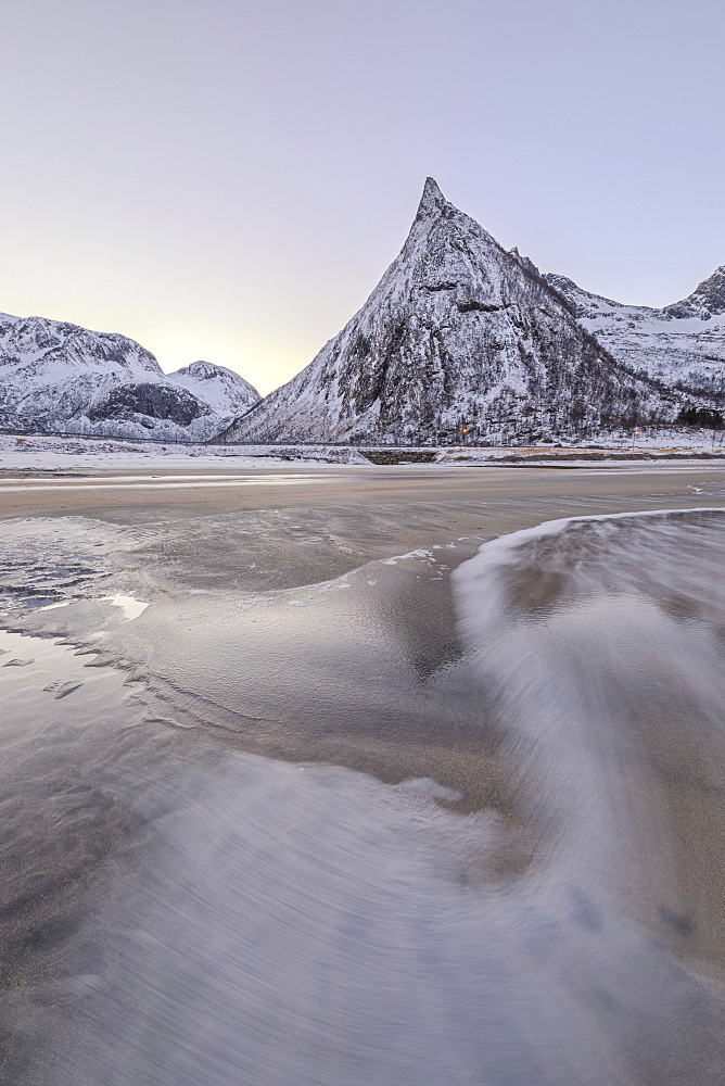 Snowy peaks and sandy beach framed by the icy waves of frozen sea at dawn, Ersfjord, Senja, Troms, Norway, Scandinavia, Europe