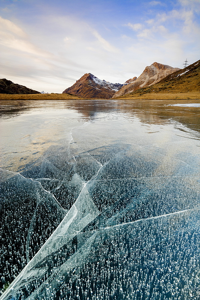 Sunset on the frozen Lej Nair surrounded by rocky peaks, Bernina Pass, Canton of Graubunden, Engadine, Switzerland, Europe