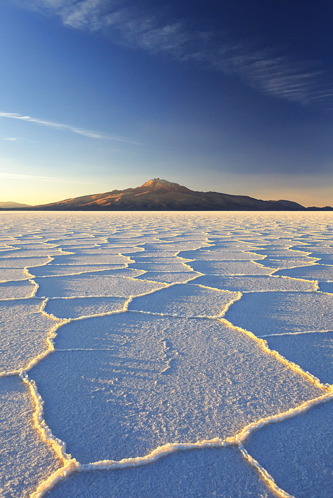 An Andean volcano rises above the Salar de Uyuni, the incredible salt desert, during a summer sunset, Oruro, Bolivia, South America