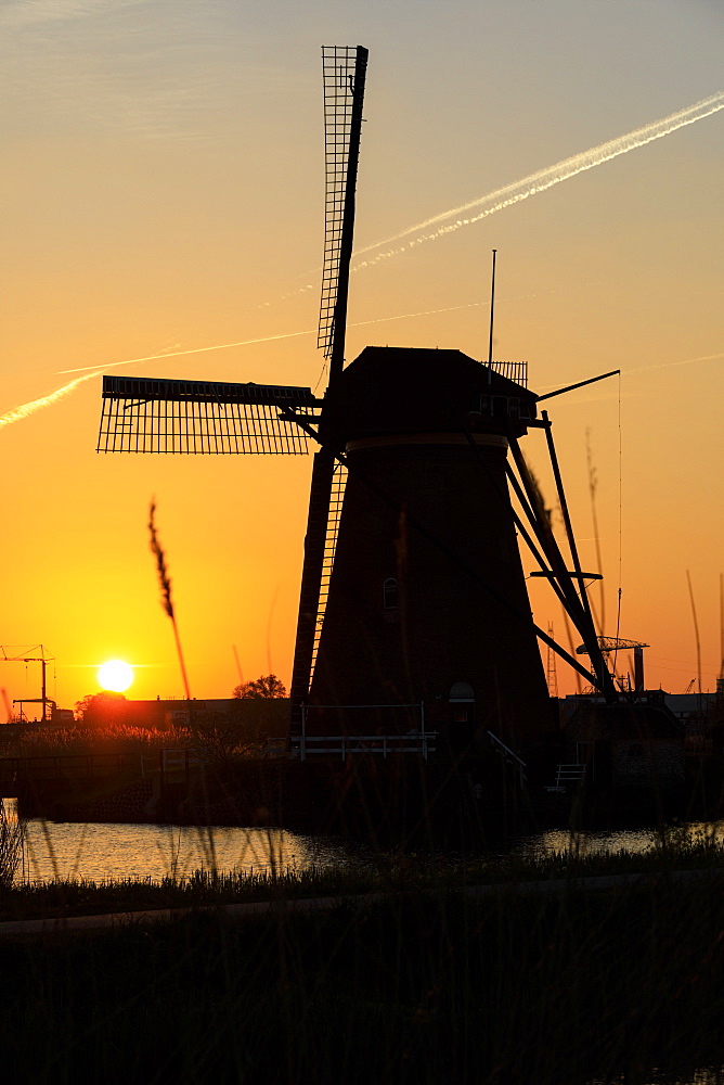 Silhouette of typical windmill framed by the fiery sky at sunset, Kinderdijk, UNESCO World Heritage Site, Molenwaard, South Holland, The Netherlands, Europe