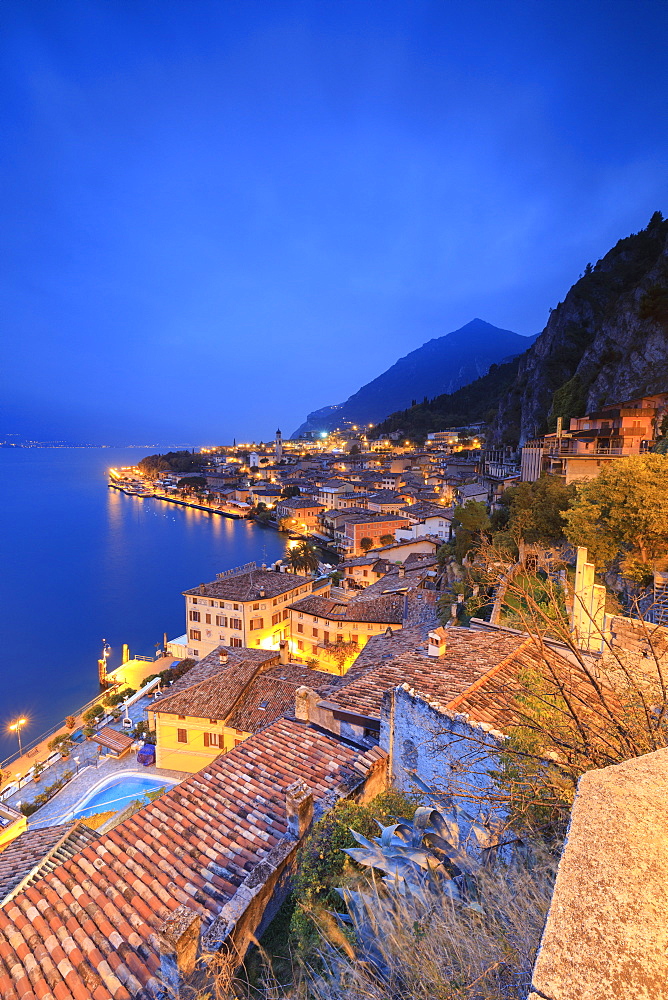 Dusk lights up Lake Garda and the typical town of Limone Sul Garda, province of Brescia, Italian Lakes, Lombardy, Italy, Europe