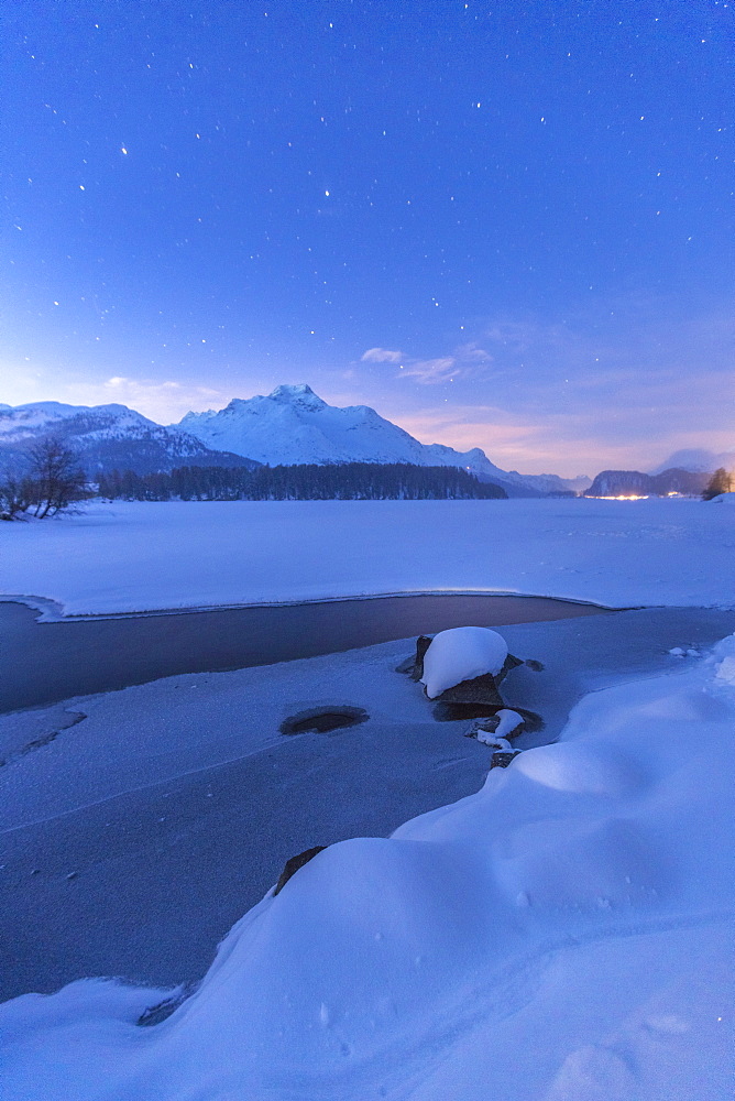 Stars above Piz Da La Margna and icy Lake Sils, Maloja, Engadine, Canton of Graubunden, Switzerland, Europe