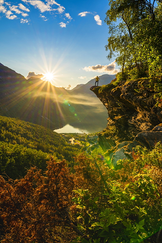 Rear view of man on top of rocks admiring Geiranger at sunset, Stranda municipality, Sunnmore, More og Romsdal county, Norway, Scandinavia, Europe