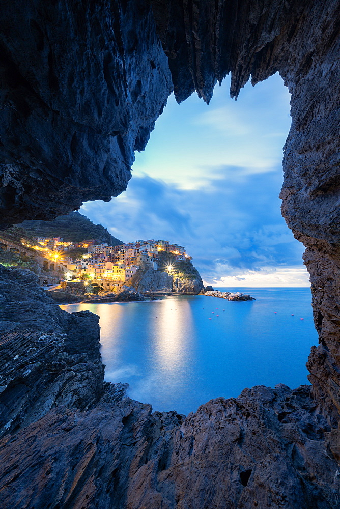 Dusk lights over Manarola seen from a sea cave, Cinque Terre, UNESCO World Heritage Site, La Spezia province, Liguria, Italy, Europe