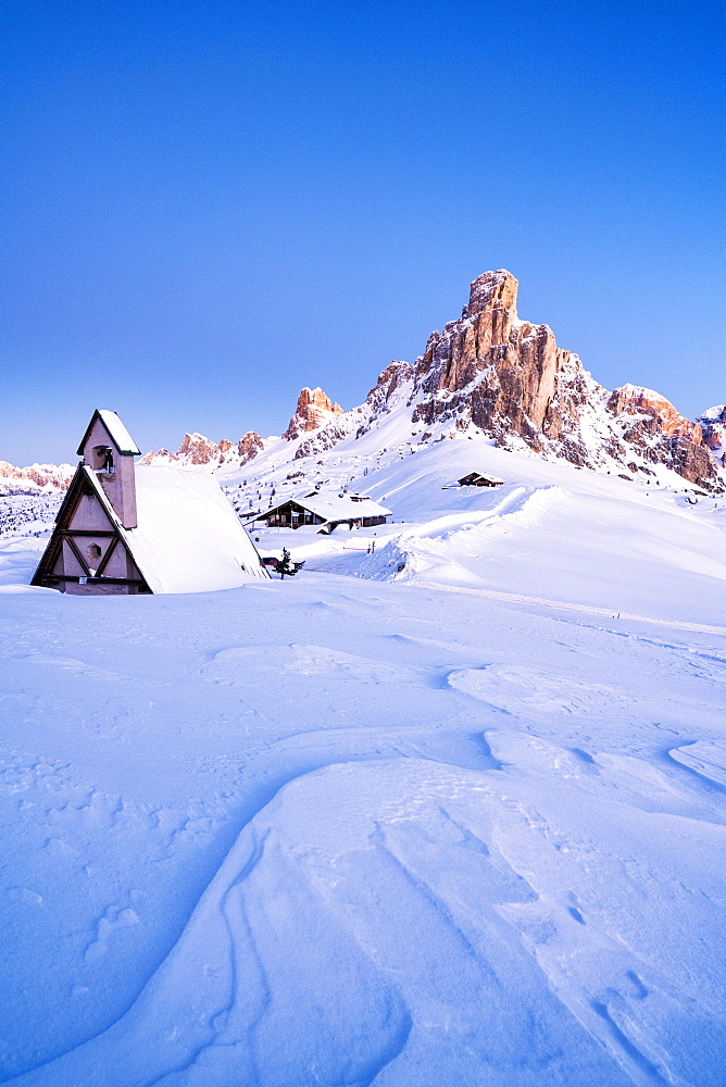 Dusk on the alpine chalet covered with snow with Ra Gusela in background, Giau Pass, Dolomites, Belluno province, Veneto, Italy, Europe