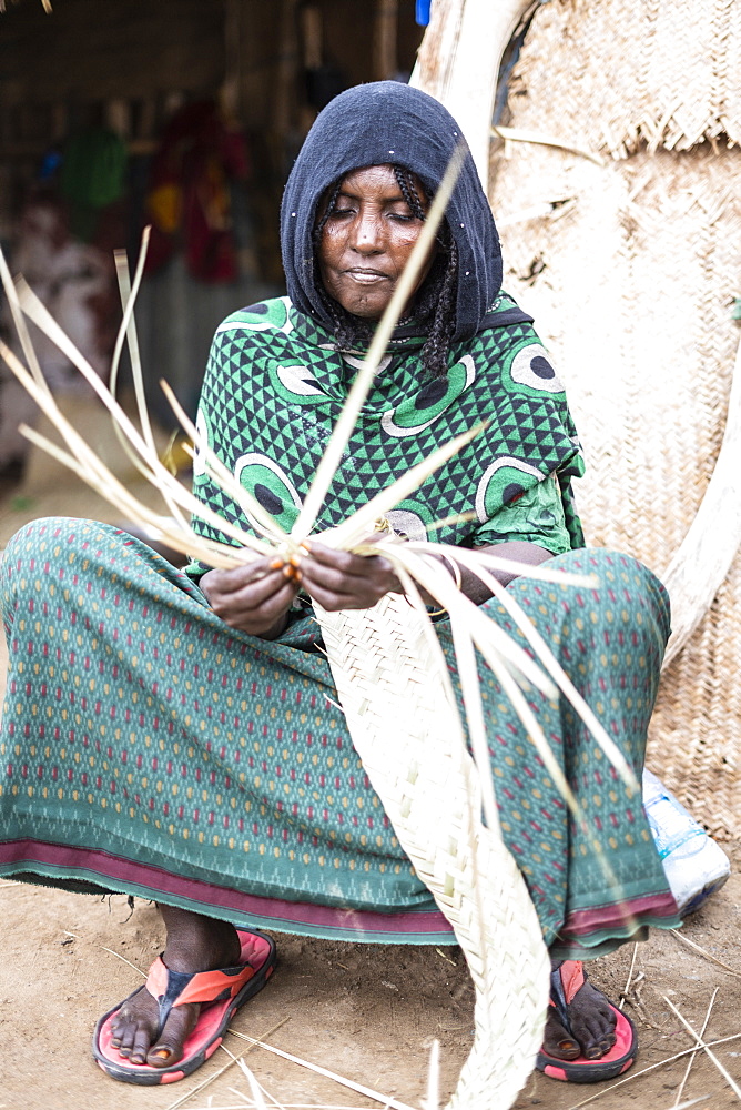 Elderly woman working with straw in Melabday village, Asso Bhole, Dallol, Danakil Depression, Afar Region, Ethiopia, Africa