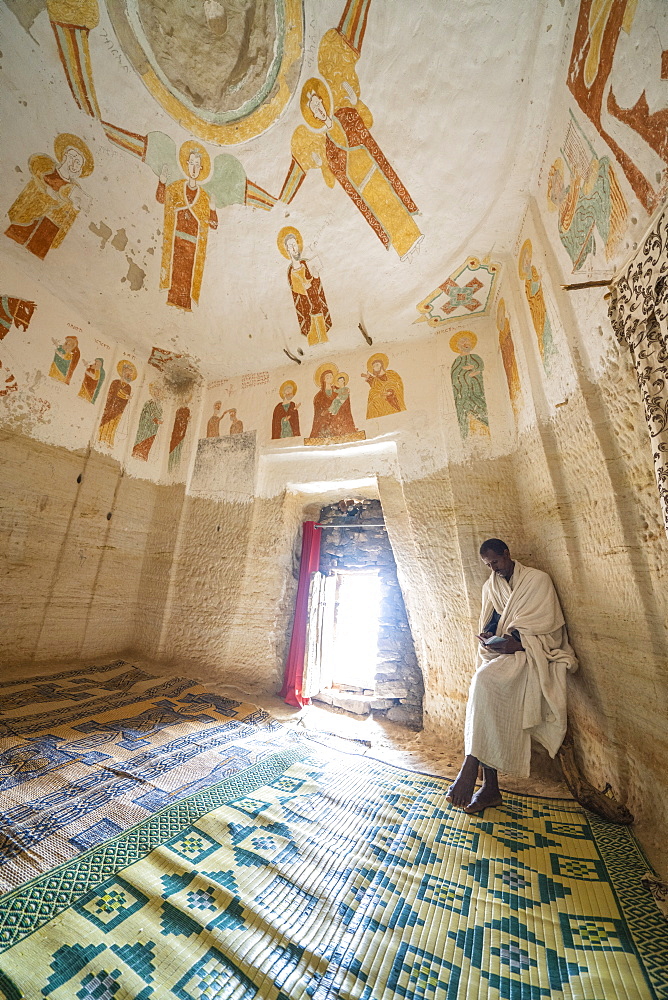 Orthodox priest holding a holy book inside Daniel Korkor church, Gheralta Mountains, Tigray Region, Ethiopia, Africa