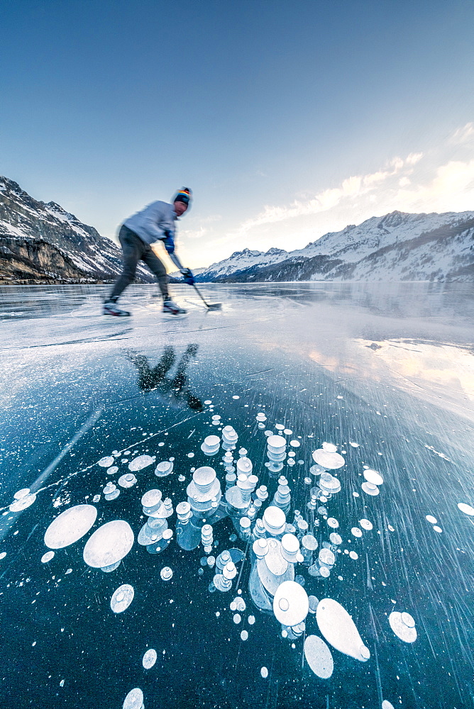 Man playing ice hockey on frozen Lake Sils, Engadine, canton of Graubunden, Switzerland, Europe