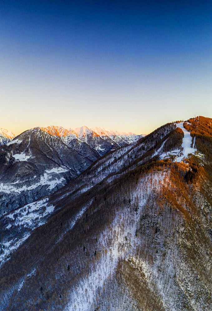 Aerial view by drone of ski slopes of Pian Delle Betulle and Alpe Paglio lit by sunset, Valsassina, Lecco province, Lombardy, Italy, Europe