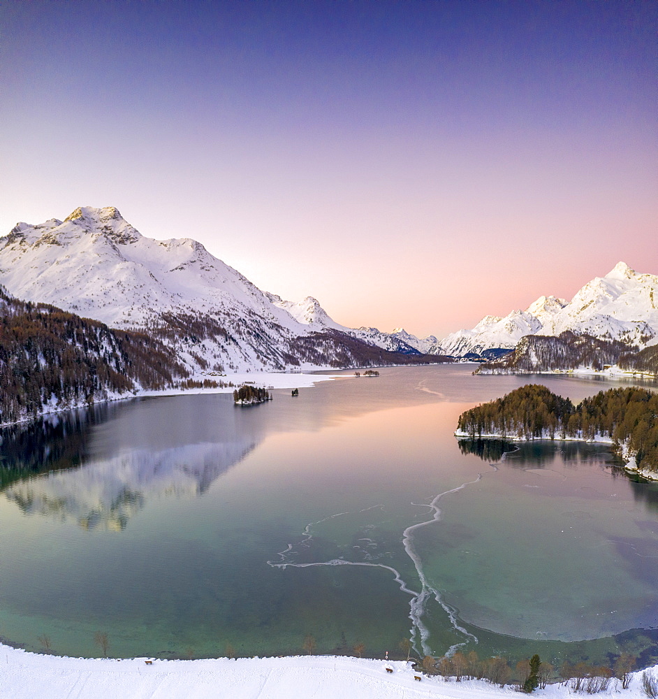 Pink sunrise on frozen Lake Sils and Piz Da La Margna covered with snow, Engadine, canton of Graubunden, Switzerland, Europe