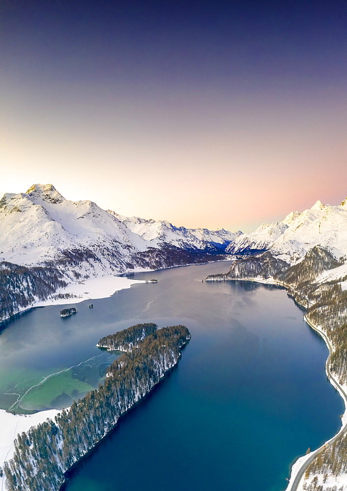 Aerial view by drone of snow capped Piz Da La Margna and Lake Sils at sunrise, Engadine, canton of Graubunden, Switzerland, Europe