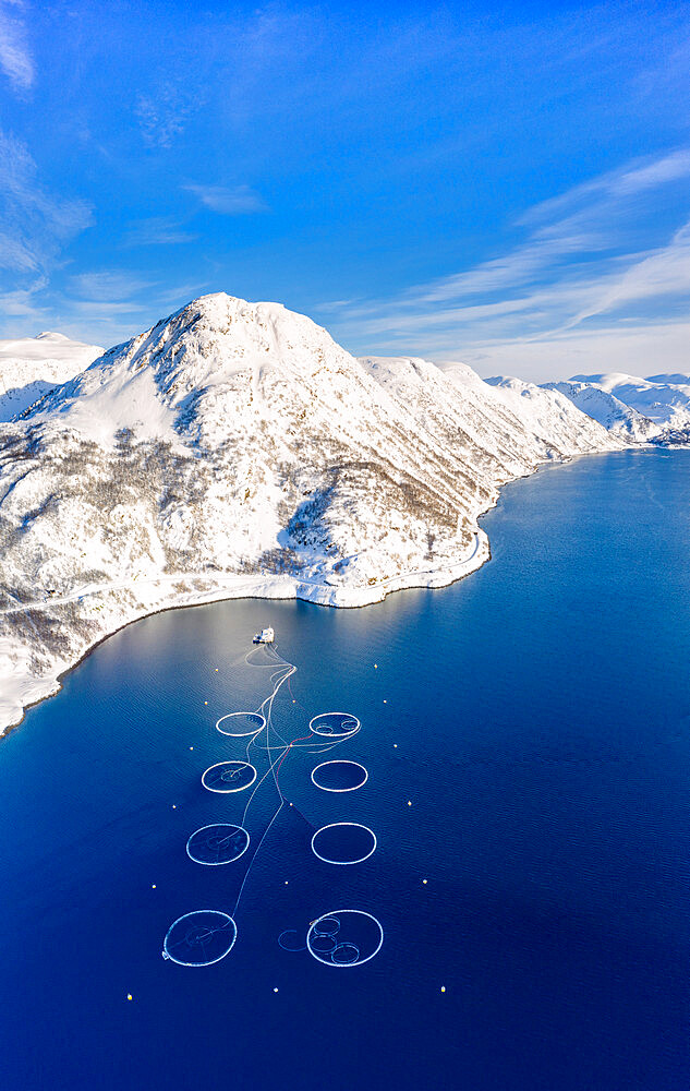 Aerial view of snow capped mountains and salmon fish farm in the Arctic sea, Oksfjord, Loppa, Troms og Finnmark, Norway, Scandinavia, Europe