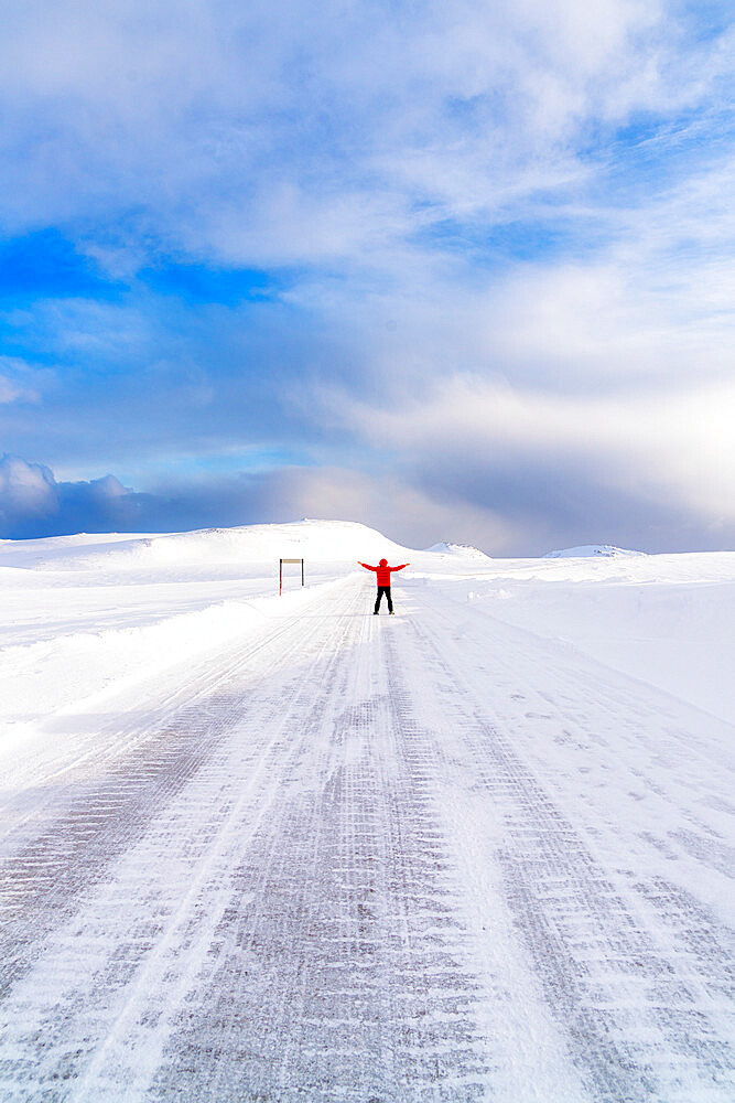 Happy man with arms raised standing on the snowy icy road towards Nordkapp (North Cape), Troms og Finnmark, Northern Norway, Scandinavia, Europe