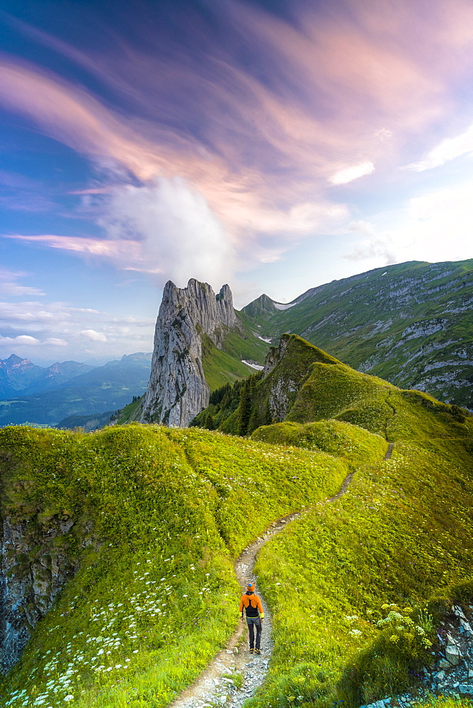 Hiker man walking on footpath towards Saxer Lucke at sunset, Appenzell Canton, Alpstein Range, Switzerland, Europe