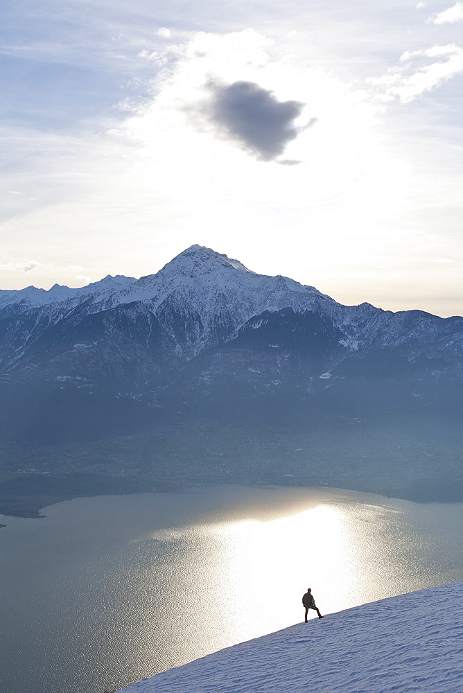 Silhoutte of a hiker facing Mount Legnone and Lake Como at sunset, Lombardy, Italy, Europe