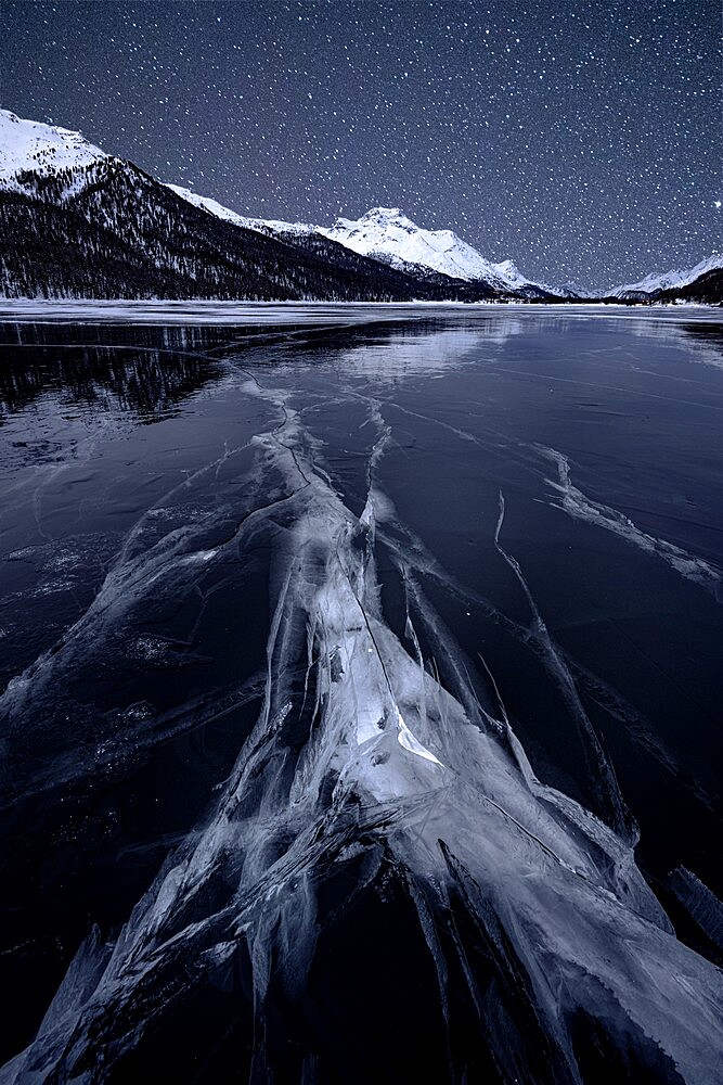 Starry night sky over the cracked ice on frozen Lake Silvaplana in winter, Maloja, Engadine, Graubunden canton, Switzerland, Europe