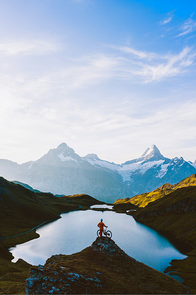 Mountain biker looking at Bachalpsee lake and Bernese Oberland mountains at dawn, Grindelwald, Bern Canton, Switzerland, Europe