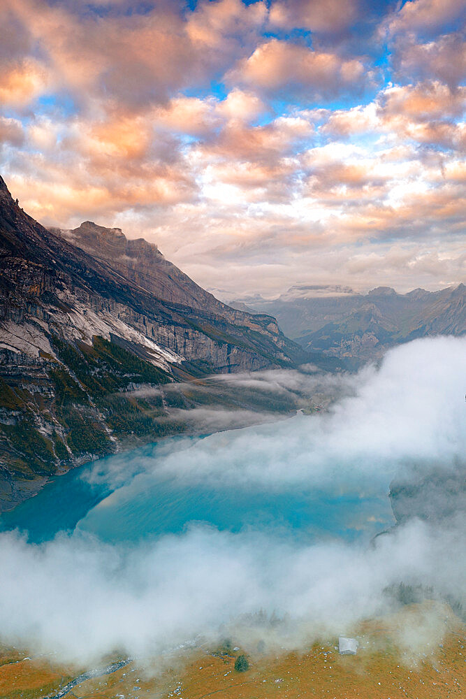 Clouds at sunset over the pristine lake Oeschinensee in the mist, Bernese Oberland, Kandersteg, canton of Bern, Switzerland, Europe