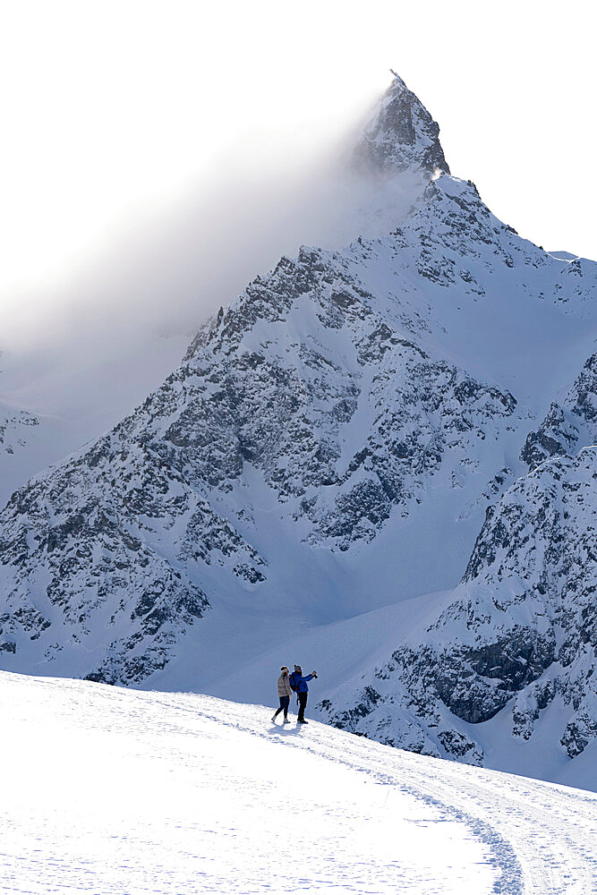 Tourists photographing the snowy peaks during a winter hike, Muottas Muragl, Samedan, Engadine, Graubunden canton, Switzerland, Europe