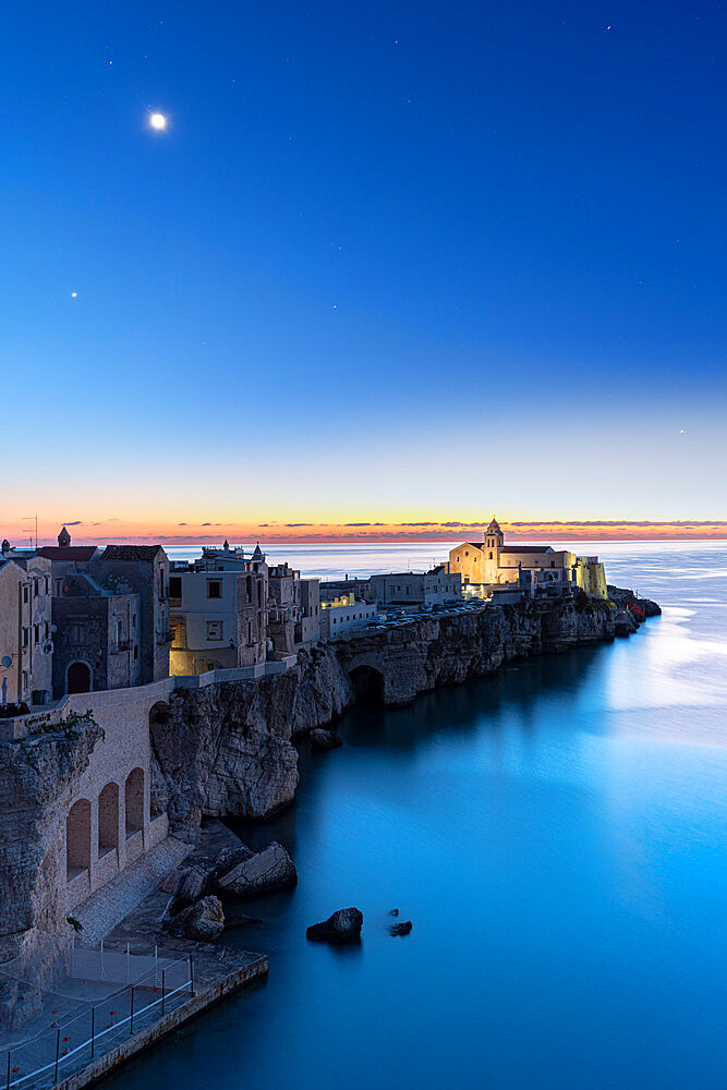 Old buildings and church of Vieste lit by moon at dusk, Vieste, Foggia province, Gargano National Park, Apulia, Italy, Europe