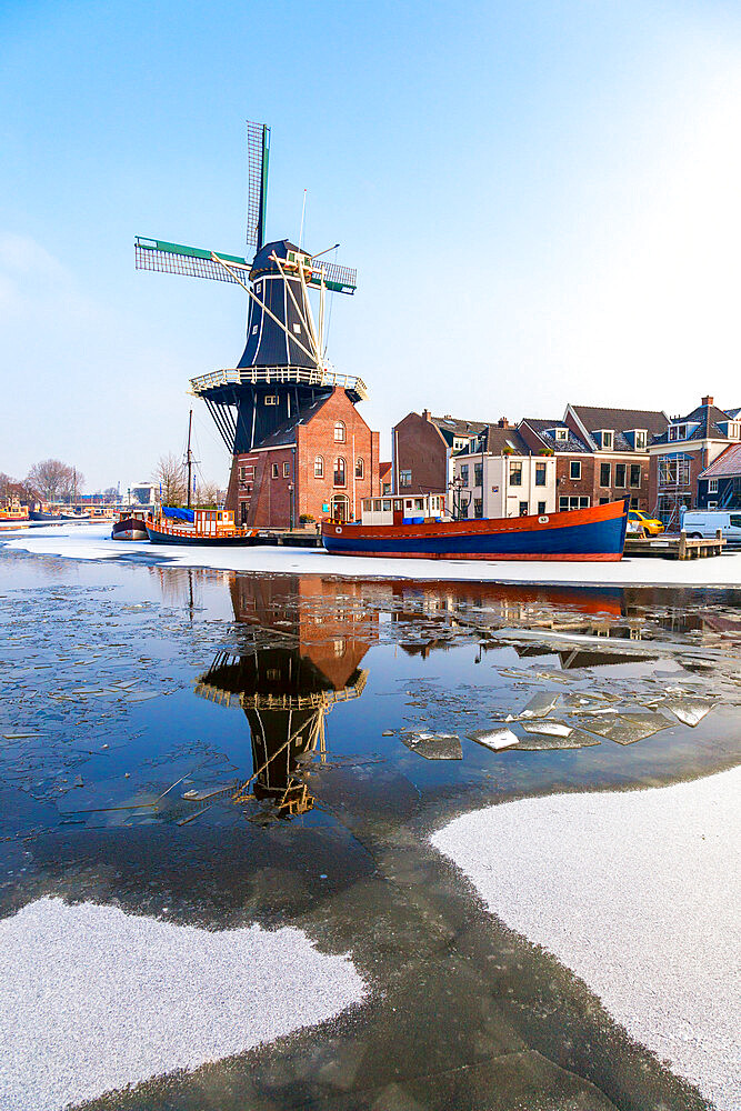 Windmill De Adriaan reflected in the canal of icy river Spaarne, Haarlem, Amsterdam district, North Holland, The Netherlands, Europe