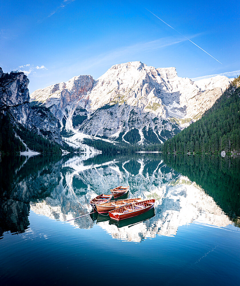 Boats moored in Lake Braies (Pragser Wildsee) with mountains reflected in water at sunrise, Dolomites, South Tyrol, Italy, Europe