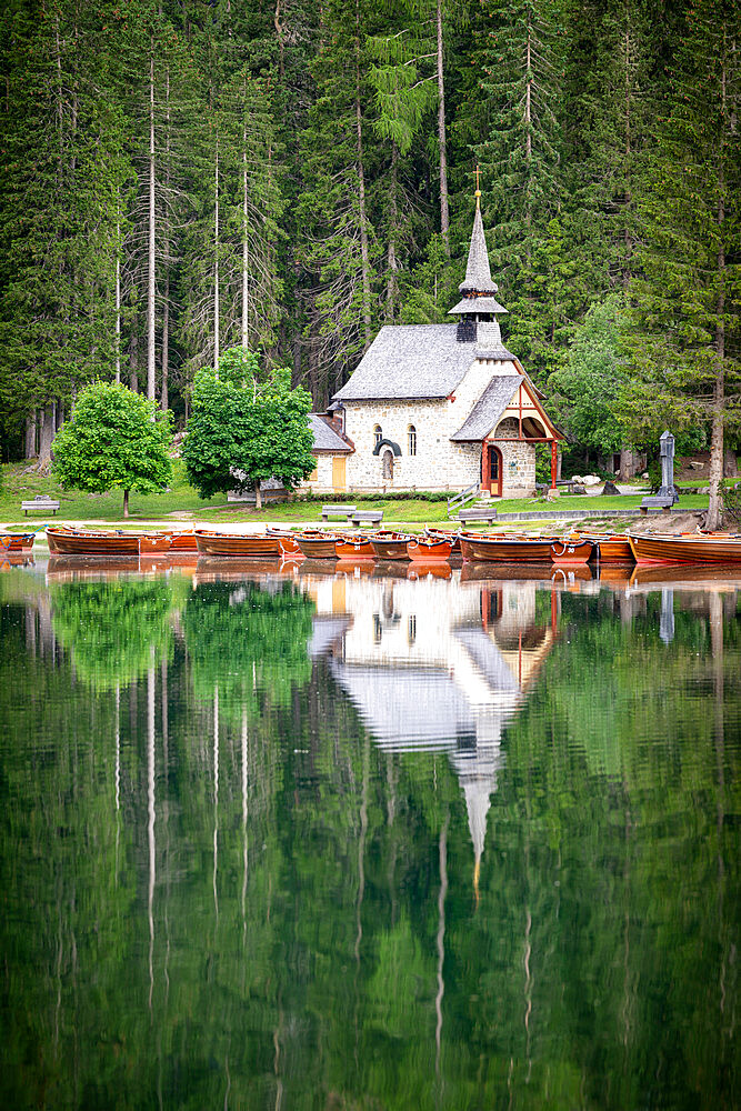 Green forest and chapel perfectly reflected in Lake Braies (Pragser Wildsee) in summer, Dolomites, South Tyrol, Italy, Europe