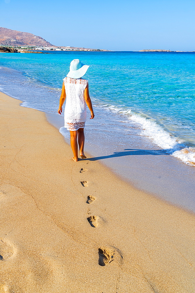 Young woman with sundress and hat walking on sand beach, Crete island, Greek Islands, Greece, Europe