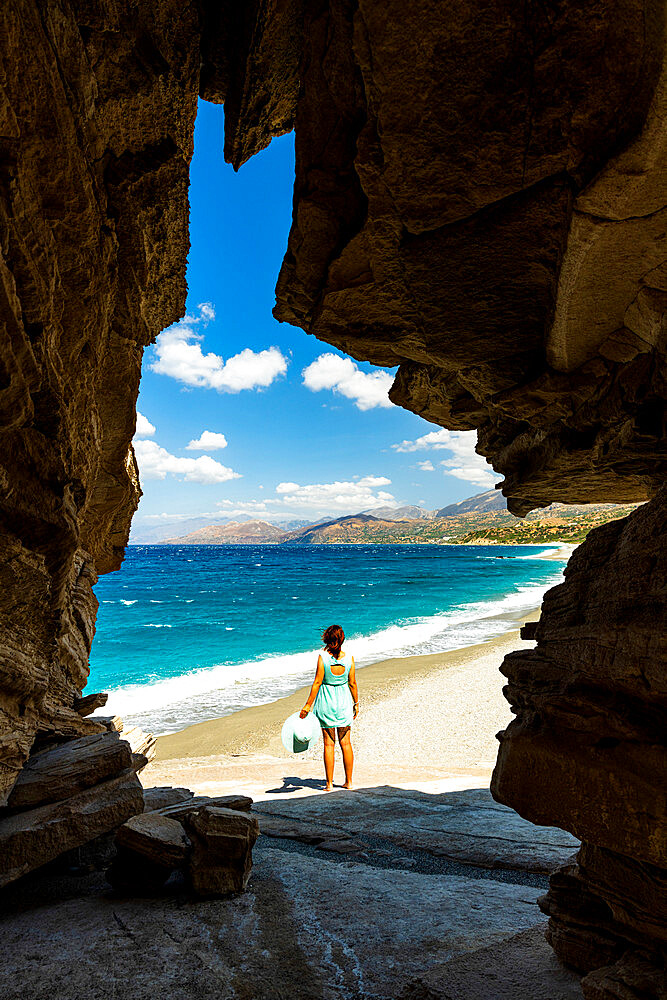 Rear view of young woman admiring the crystal sea from natural cave on Triopetra beach, Plakias, Crete, Greek Islands, Greece, Europe