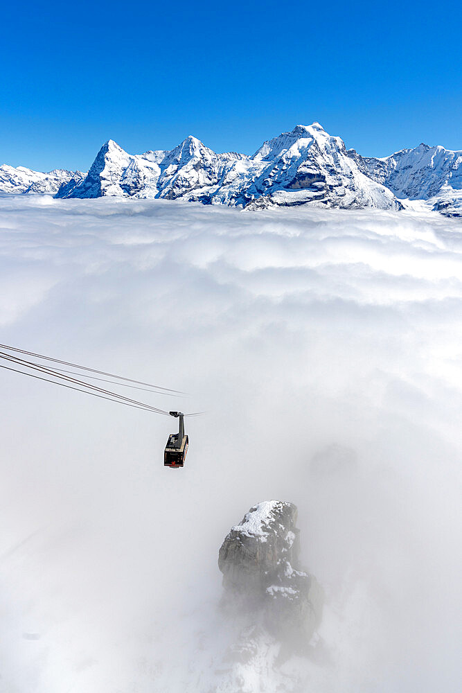 Clear sky over the snowcapped Eiger, Monch, Jungfrau peaks with Schilthorn cableway in dense fog, Bern Canton, Swiss Alps, Switzerland, Europe