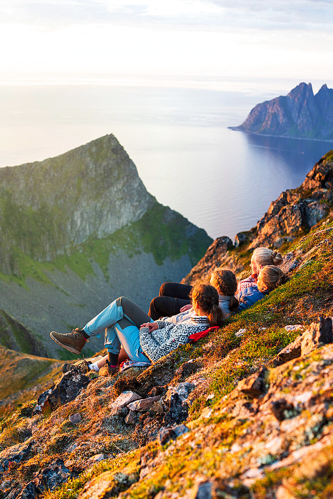 Young Scandinavian women enjoying sunset relaxing together on rocks, Senja island, Troms county, Norway, Scandinavia, Europe