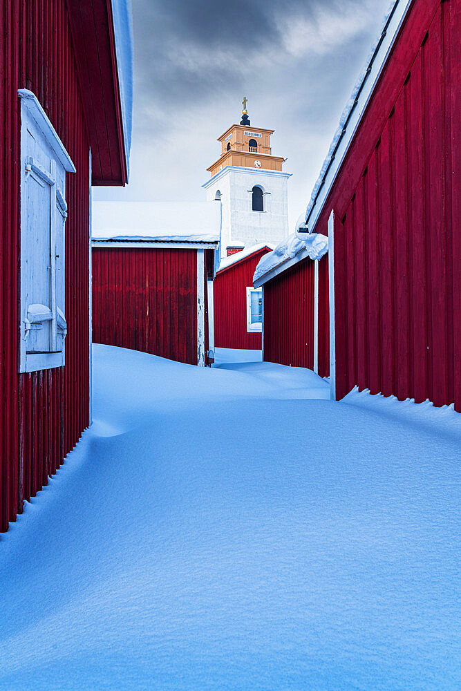 Clouds over the snow covered red cottages and bell tower, Gammelstad Church Town, UNESCO World Heritage Site, Lulea, Sweden, Scandinavia, Europe