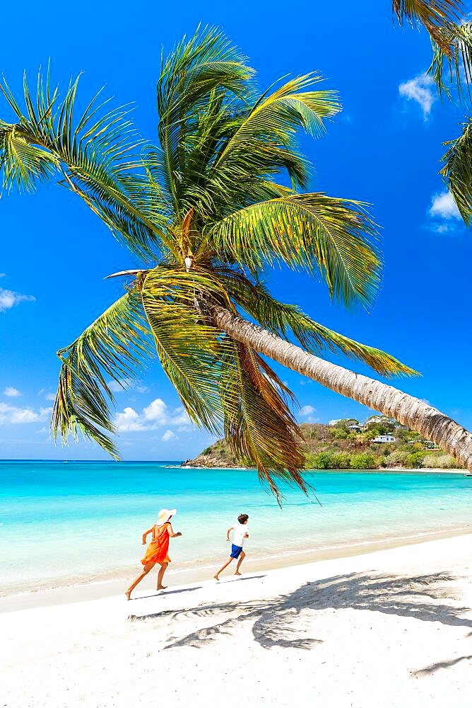 Woman and cute little boy having fun running on a palm fringed beach, Antigua, Caribbean, West Indies