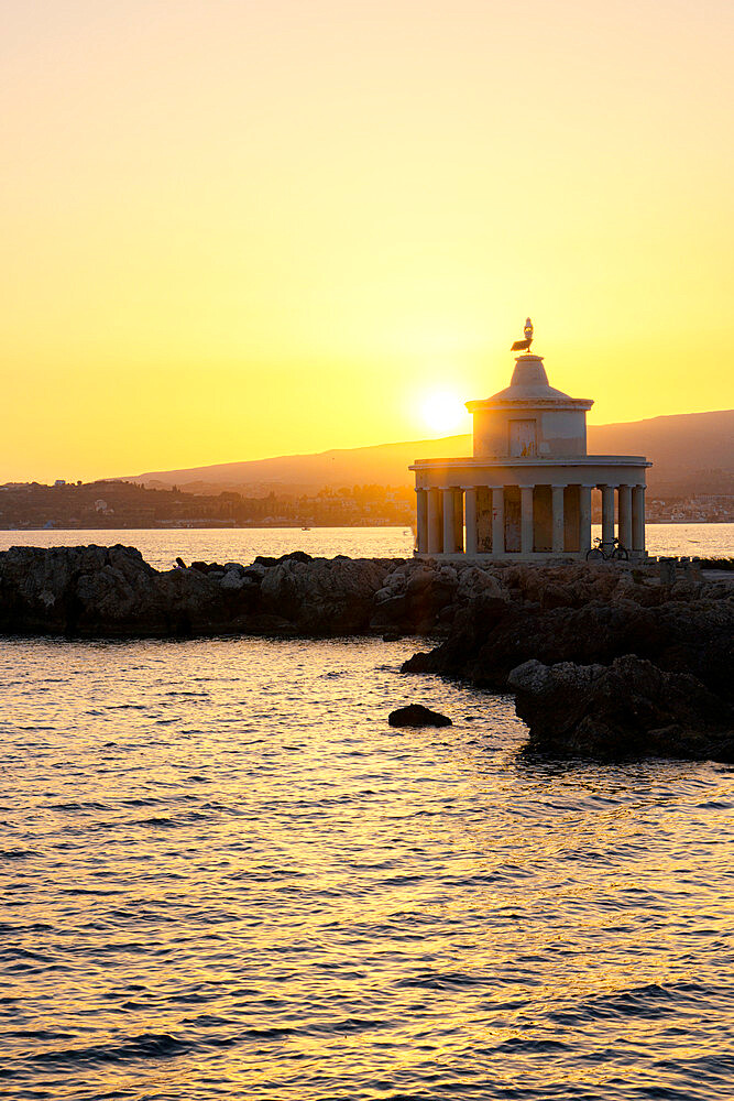 Romantic sunset over Saint Theodore lighthouse reflected in the sea, Argostoli, Kefalonia, Ionian Islands, Greek Islands, Greece, Europe