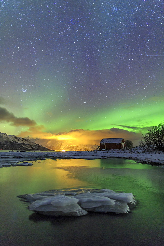 The Northern Lights illuminates the wooden cabin, Oteren, Storfjorden, Lyngen Alps, Troms, Lapland, Norway, Scandinavia, Europe