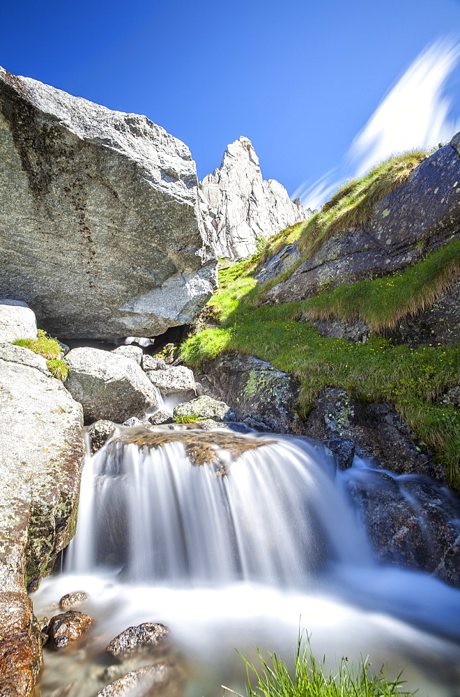 The granite peak of a mountain in Valmasino, famous among climbers, contrasting with the flowing waters of a stream, Lombardy, Italy, Europe