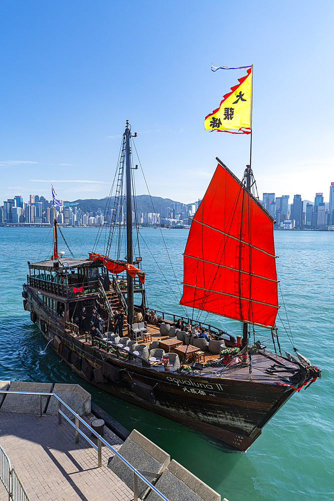 Traditional sailing boat with red sail with high rise buildings in distance, Central Hongkong, China, Asia