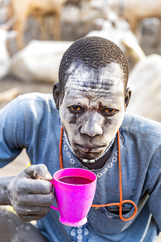 Dust covered man drinking local coffee, Mundari tribe, South Sudan, Africa