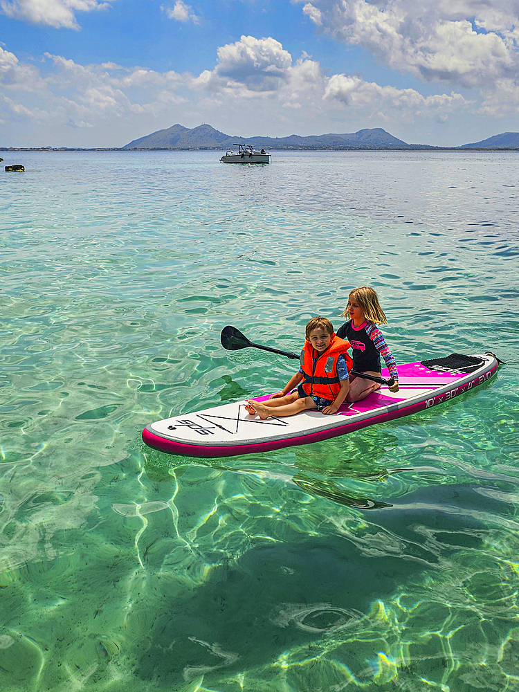 Kids on a SUP in the turquoise waters of the Formentor Peninsula, Mallorca, Balearic islands, Spain, Mediterranean, Europe