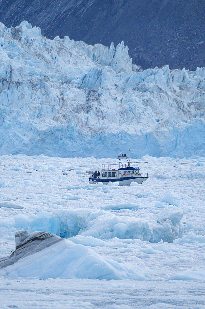 Little ship floating between the ice below the Eqi glacier, Western Greenland, Denmark, Polar Regions