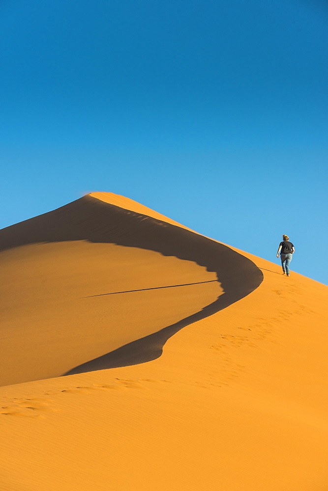 Woman hiking up the giant Sand Dune 45, Sossusvlei, Namib-Naukluft National Park, Namibia, Africa